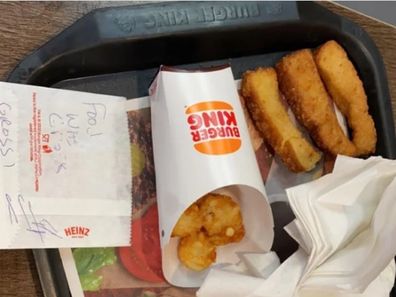 Fast food spread messily on a tray with a note reading "Food was gross".