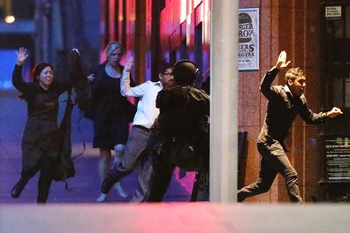 People flee from the Lindt Cafe, Martin Place during a hostage standoff on December 16, 2014 in Sydney, Australia. Police stormed the Sydney cafe  where lone gunman, Man Haron Monis, had been holding ten customers and eight employees. Hostage Tori Johnson was killed by Monis and hostage Katrina Dawson was killed by a police bullet ricochet during the raid. Monis was killed by police. 