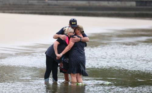 Tweed Heads locals console each other as they lay flowers in the water at Jack Evans Boat Harbour.