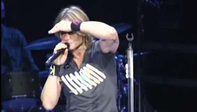 Keith Urban with fan on stage.