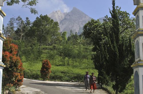 Villagers walk as Mount Merapi is seen in the background in Pemalang, Central Java. Picture: AAP