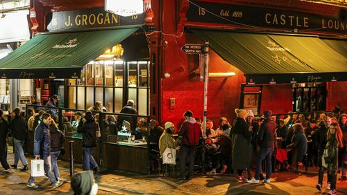 Les gens socialisent à Temple Bar dans le centre-ville de Dublin tard dans la soirée après l'assouplissement des restrictions sur les coronavirus à travers l'Irlande, le samedi 22 janvier 2022. 