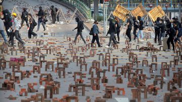 Protesters walk past barricades of bricks on a road near the Hong Kong Polytechnic University in Hong Kong.