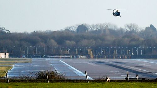 A police helicopter flies over the runway at Gatwick Airport, London, as the airport remains closed with incoming flights delayed or diverted to other airports, after drones were spotted.