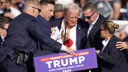 Republican presidential candidate former President Donald Trump is helped off the stage at a campaign event.