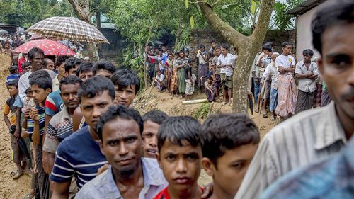 Newly arrived Rohingya Muslims wait for their turn to collect building material for their shelters distributed by aid agencies in Kutupalong refugee camp, Bangladesh. (AAP)