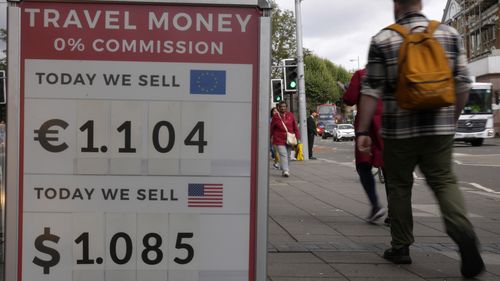 Pedestrians pass a currency exchange sign outside a shop in London, on September 23, 2022. 