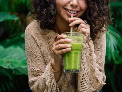 Stock photo: woman smiling with a juice and acne on her skin.