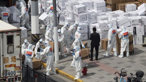 Workers unload supplies including boxes of masks in Shanghai as the city begins lifting some of its strict COVID-19 restrictions.
