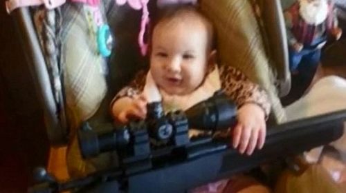 Baby holds a rifle in shocking photo