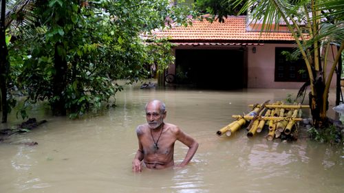 An elderly man wades through flood waters to reach a boat carrying food supplies for stranded people in Chengannur in the southern state of Kerala, India.