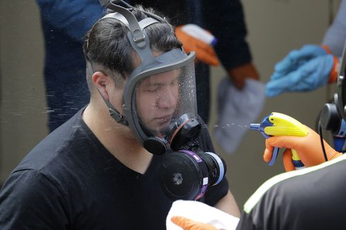 A Servpro cleaning worker has his respirator mask sprayed down Thursday, March 12, 2020, as he gets ready for a break from his work cleaning inside the Life Care Center in Kirkland, Wash., near Seattle. Picture: Ted S. Warren
