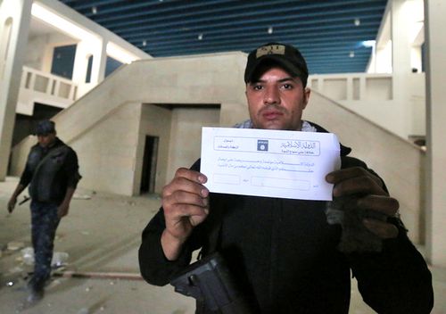 A member of the Iraqi government forces holds an envelope from the office of the self-proclaimed Islamic State (ISIL) group charity and alms office calling for the rich to donate to the poor, which is known in Islam as "Zakat". Source: AFP