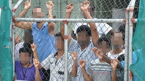 Refugees at Manus Island peer through a security fence. (AAP)