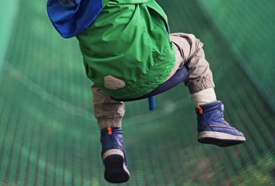 Little boy zipping on zip line in outdoors amusement park.