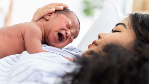 Una nueva madre sostiene a su bebé llorando.