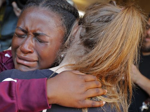 Marla Eveillard, 14, cries as she hugs friends before the start of a vigil at the Parkland Baptist Church, for the victims. Picture: AAP
