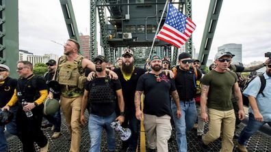 Members of the Proud Boys and other right-wing demonstrators march across the Hawthorne Bridge during a rally in Portland last year. The group includes organiser Joe Biggs, in a green hat, and Proud Boys Chairman Enrique Tarrio, holding the megaphone.