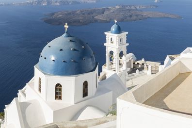 Early morning view in Santorini of the Imerovigli church sitting on top of the volcanic caldera. Santorini in Greece is one of the most famous travel destination in the World with numerous cruise ships anchoring in the bay below. The architecture is also famous for the duotone colors of the white painted buildings and light blue details.