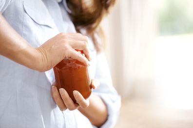 Image of a woman trying to open a jar in the kitchen