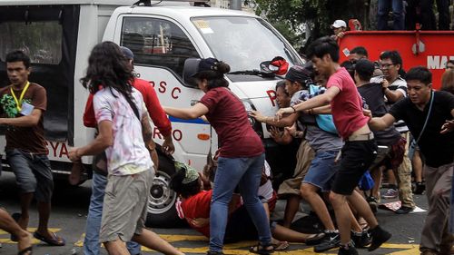 A police mobile runs over protesters during a protest in front of the US Embassy in Manila. (AAP)