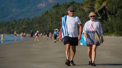 People walk along on a beach on North Queensland, as Cairns faces a COVID-19 scare and snap three-day lockdown.