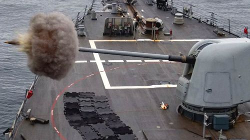 A US Navy vessel fires a shell from its five-inch deck gun.