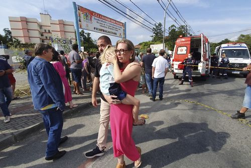 A woman conforts a crying girl outside the daycare center "Cantinho do Bom Pastor" after a fatal attack on children in Blumenau, Santa Catarina state, Brazil, Wednesday, April 5, 2023. 