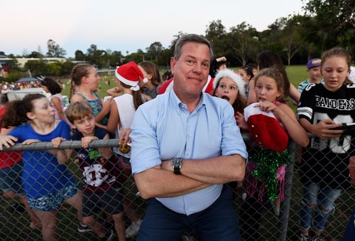 Tim Nicholls with schoolchildren behind him after doing a live cross at the Jindalee State School Christmas carols. (AAP)