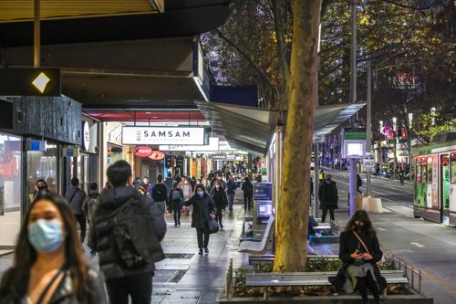 Shoppers and pedestrians in masks walk down Swanston Street in Melbourne's CBD. 