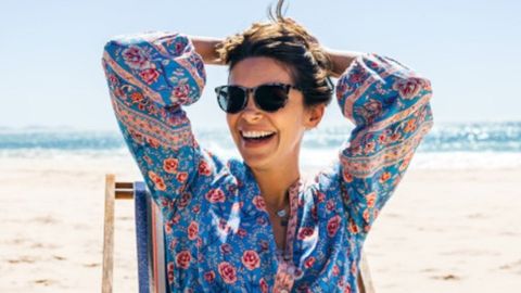 Woman on beach wearing sunglasses. 