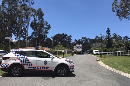 Police officers and detectives are seen at the scene of the discovery of a woman's body on the street outside her home in Worongary. (AAP)