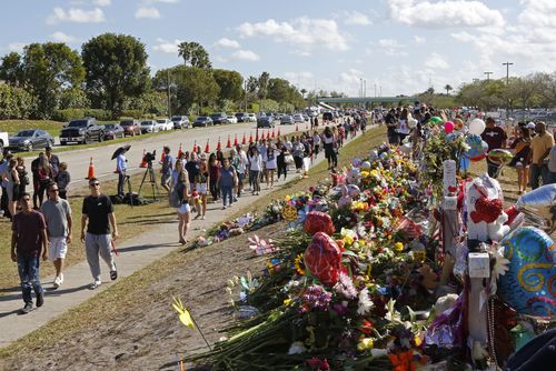 Parents and students walk by the memorial for the victims of the shooting. (AAP)