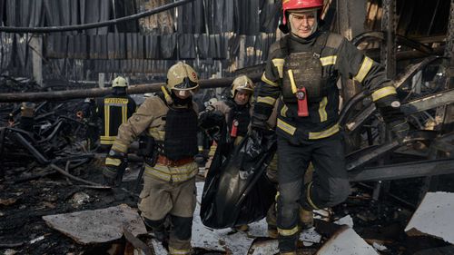 Emergency workers carry out the body of a victim of a Russian strike that hit a large store in Kharkiv.