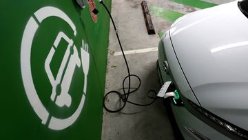 A Hyundai KONA Electric charges at a EV charge station.