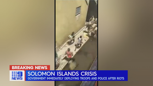 People appear to flee down an alleyway as unrest intensifies in the Solomon Islands capital of Honiara.