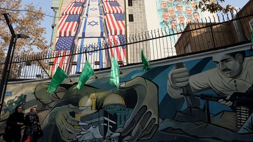 Women walk past an anti-US and anti-Israel billboard displayed on a building in Tehran, Iran on January 4.