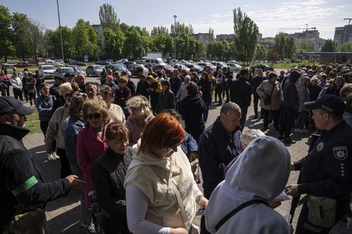 FILE - People stand in line for registration at the aid distribution center for displaced people in Zaporizhzhia, Ukraine, on May 5, 2022. The Russian ruble is now the official currency in the Kherson region, on par with the Ukrainian hryvnia. Russian passports are being offered in Moscow-controlled parts of the Zaporizhzhia region in a fast-track procedure.(AP Photo/Evgeniy Maloletka, File)