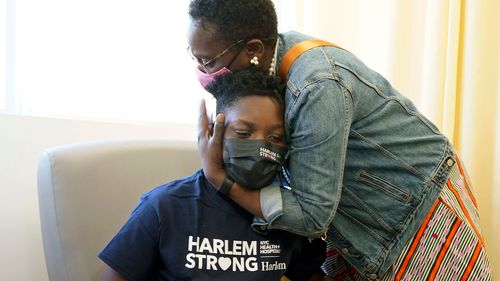 Julian Boyce, 14, gets a hug from his mother, Satrina Boyce, after he received his first Pfizer COVID-19 vaccination dose in New York.