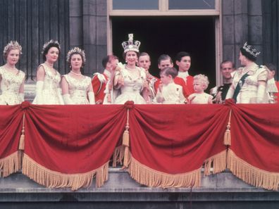 2nd June 1953:  The newly crowned Queen Elizabeth II waves to the crowd from the balcony at Buckingham Palace. Her children Prince Charles and Princess Anne stand with her.  (Photo by Hulton Archive/Getty Images)