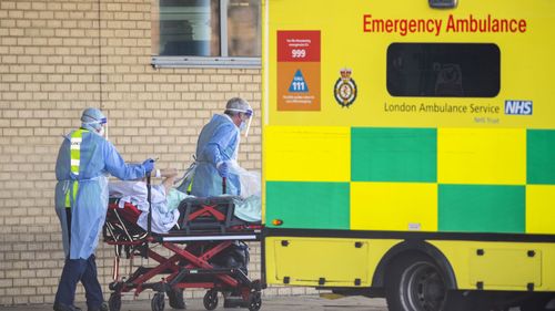 NHS workers in PPE take a patient with an unknown condition to an ambulance at Queens Hospital on April 21, 2020 in London, England