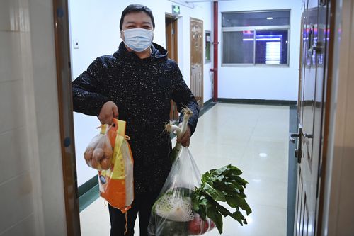 In this photo released by Xinhua News Agency, a a community worker holds up daily necessities delivered to a household under closed-off management in Xi'an, capital of northwest China's Shaanxi Province, Dec. 29, 2021. Chinese officials promised steady deliveries of groceries to residents of Xian, an ancient capital with 13 million people that is under the strictest lockdown of a major Chinese city since Wuhan was shut early last year at the start of the pandemic. (Tao Ming/Xinhua via AP)