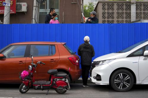 Los residentes conversan detrás de la valla fortificada de un complejo de apartamentos cerrado en Beijing.