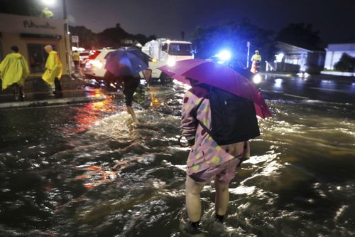 People cross a flooded street in Auckland, Friday, Jan. 27, 2023. Record levels of rainfall pounded New Zealand's largest city, causing widespread disruption.  