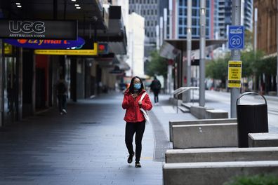 A woman wearing a face mask walks along George street in Sydney's CBD on April 8. Many people are working from home to help stop the spread of the coronavirus.