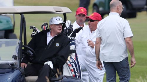 Trump had a chat with his staff while seated on his golf buggy. Picture: AAP