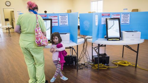 Scarlette Martin, 4, waits as her mum, Jocelyn Martin, casts her vote in Georgia's US Senate runoff election.