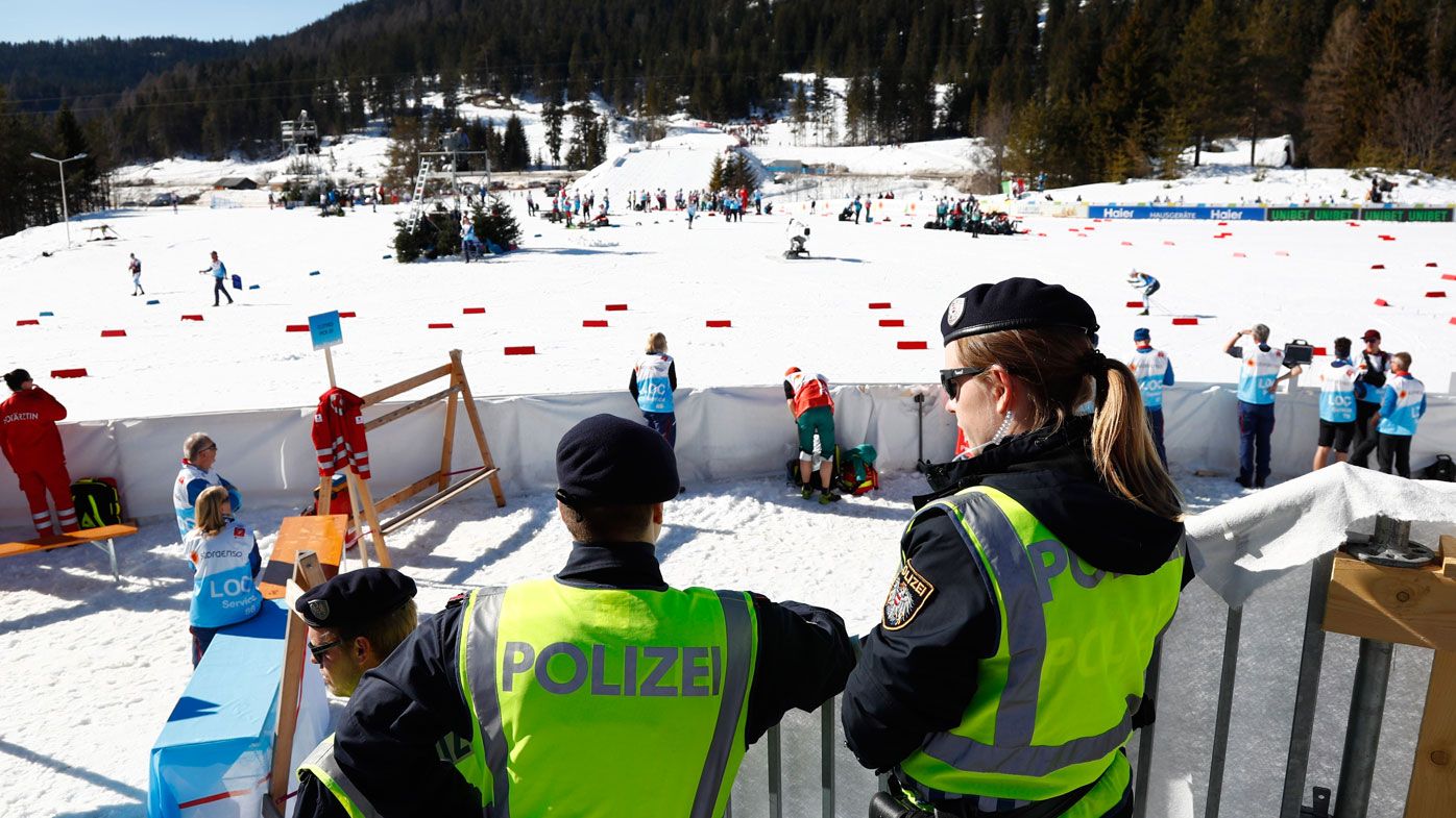 Austrian Federal Police officers stand at the finish area of a men's cross country skiing