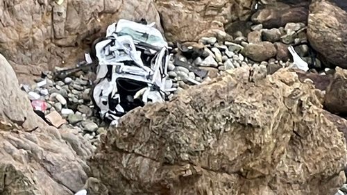 The Tesla is seen on a rocky beach below the cliffs, an area called Devil's Slide.