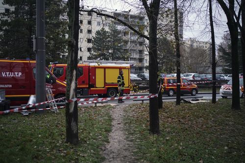 Un pompier se tient près de camions ambulanciers à côté d'immeubles d'appartements vus en arrière-plan dans le quartier du Mas du Taureau, à Vauls en Velin, à l'extérieur de Lyon, 
